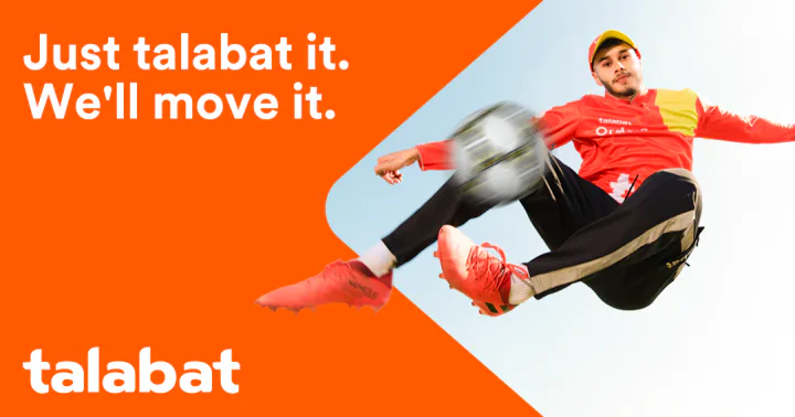 Key creative — a player in a red-and-yellow top kicks a ball overhead against a pale sky, beside the orange panel and the talabat logo