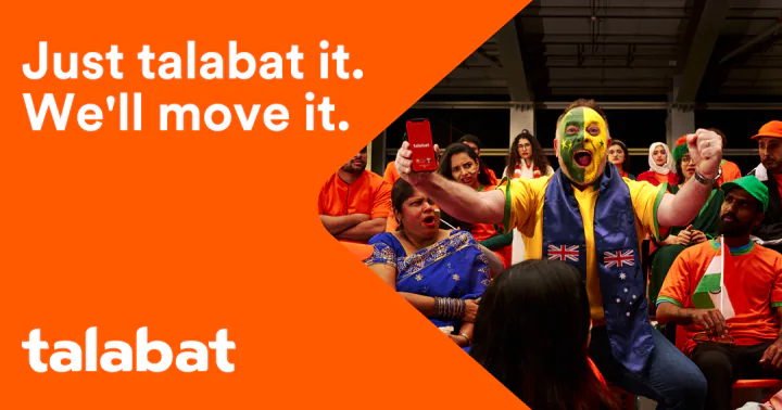Key creative — a fan with a green-and-yellow painted face and a scarf printed with the Australian flag raises a phone among fans in orange shirts, beside the orange panel and the talabat logo