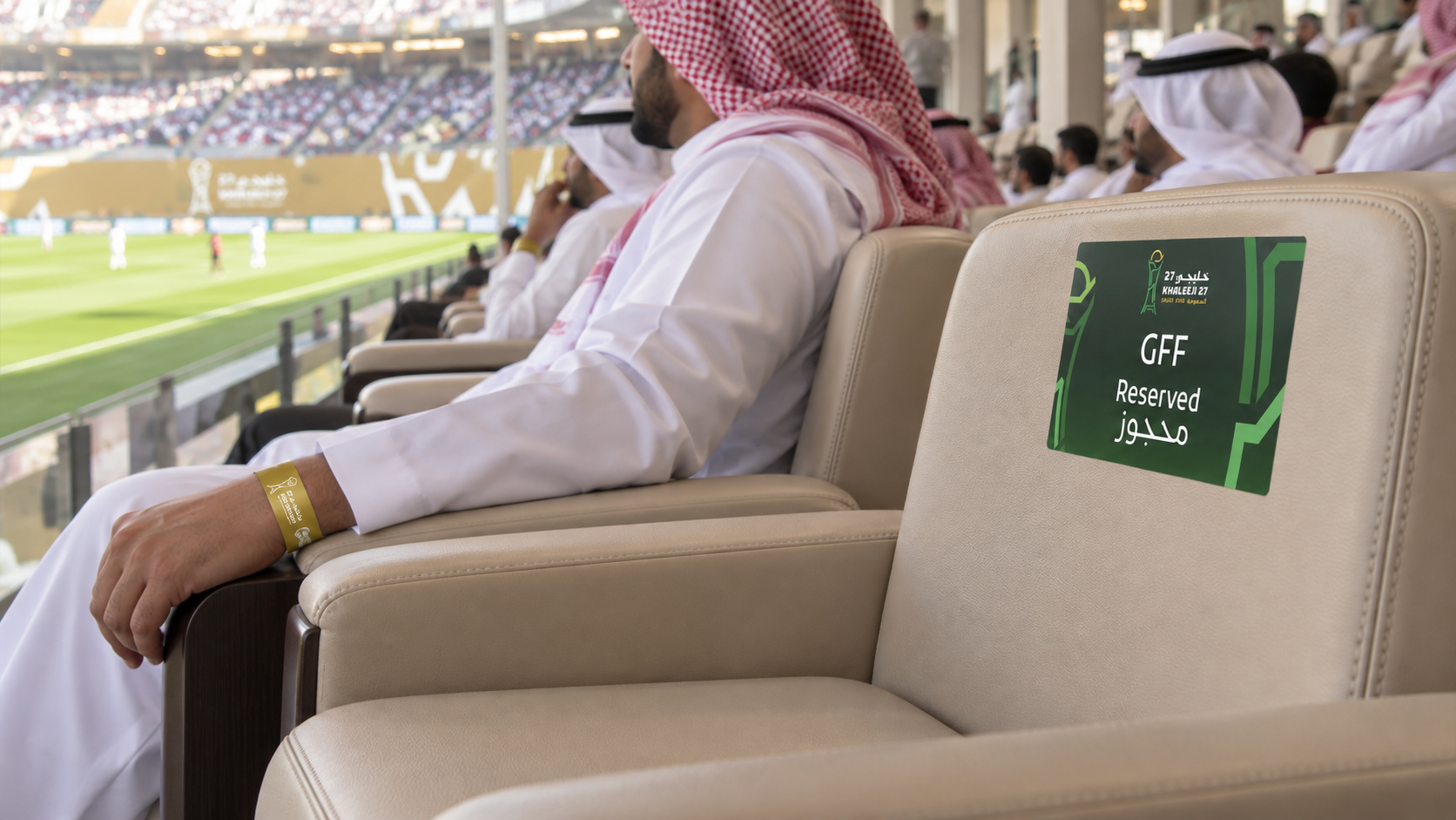 Hospitality chairs facing the pitch, with a reserved-seat sticker and a wristband on the adjacent guest
